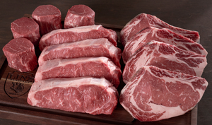Pictured are  4 each of uncooked Linz Heritage Angus tenderloin filets, strip steaks, and ribeyes on a cutting board.